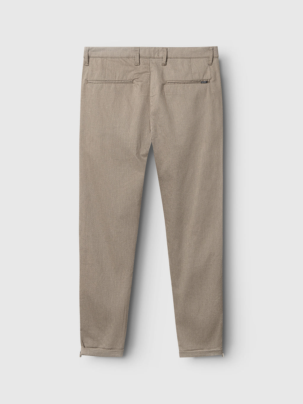 Back view of the GABBA Pisa K3280 Dale Pants in Humus: slim-fit light brown trousers with two rear welt pockets, a black brand tag on the right pocket, ankle zippers, and made from high-stretch fabric for comfort and ease of movement.