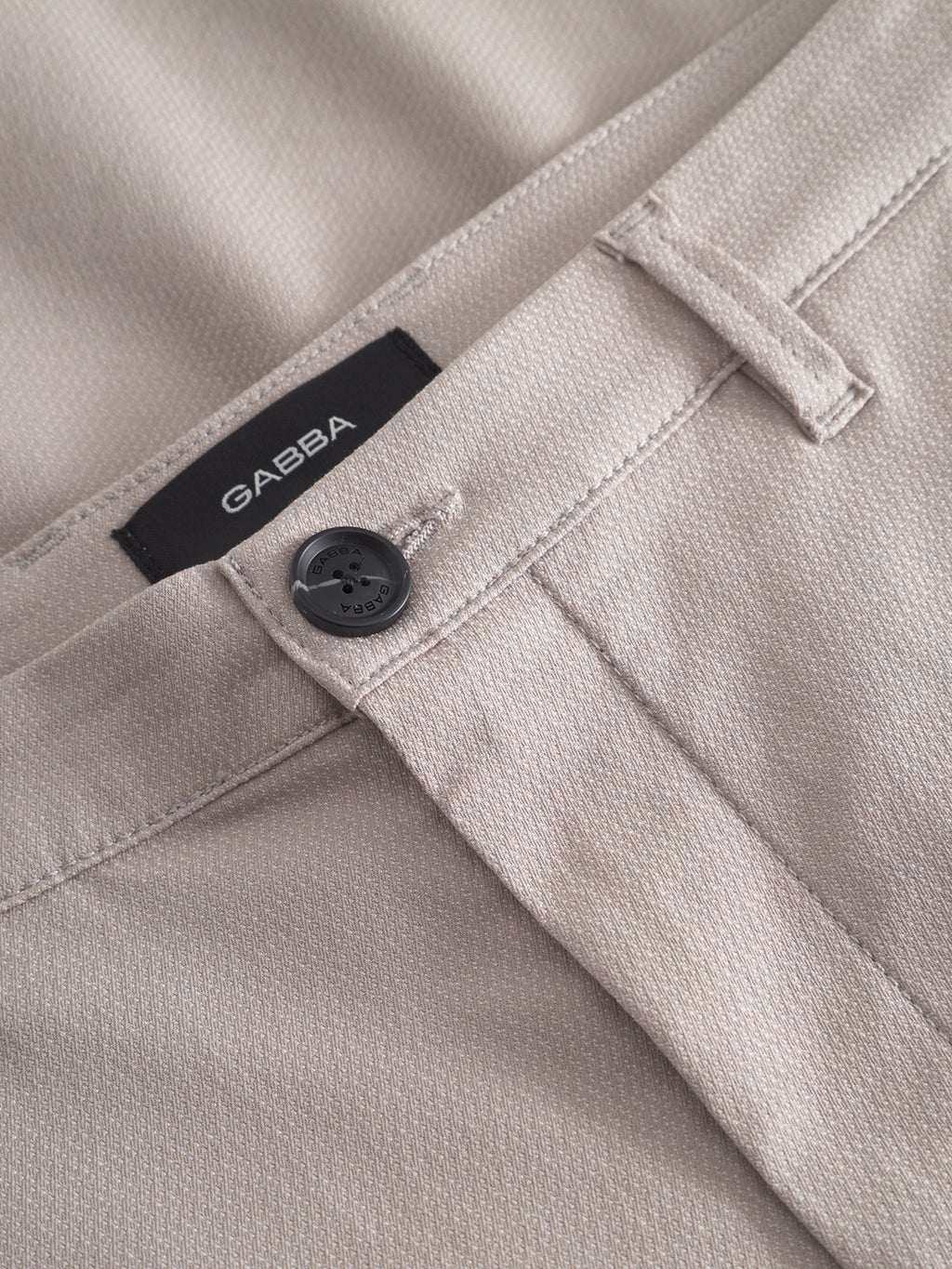 Close-up of a pair of Gabba Pisa K3280 Dale Pants in Grey Paloma, with a black button and Gabba label. The high-stretch fabric has a subtle texture, featuring visible stitching at the waistband and belt loops.