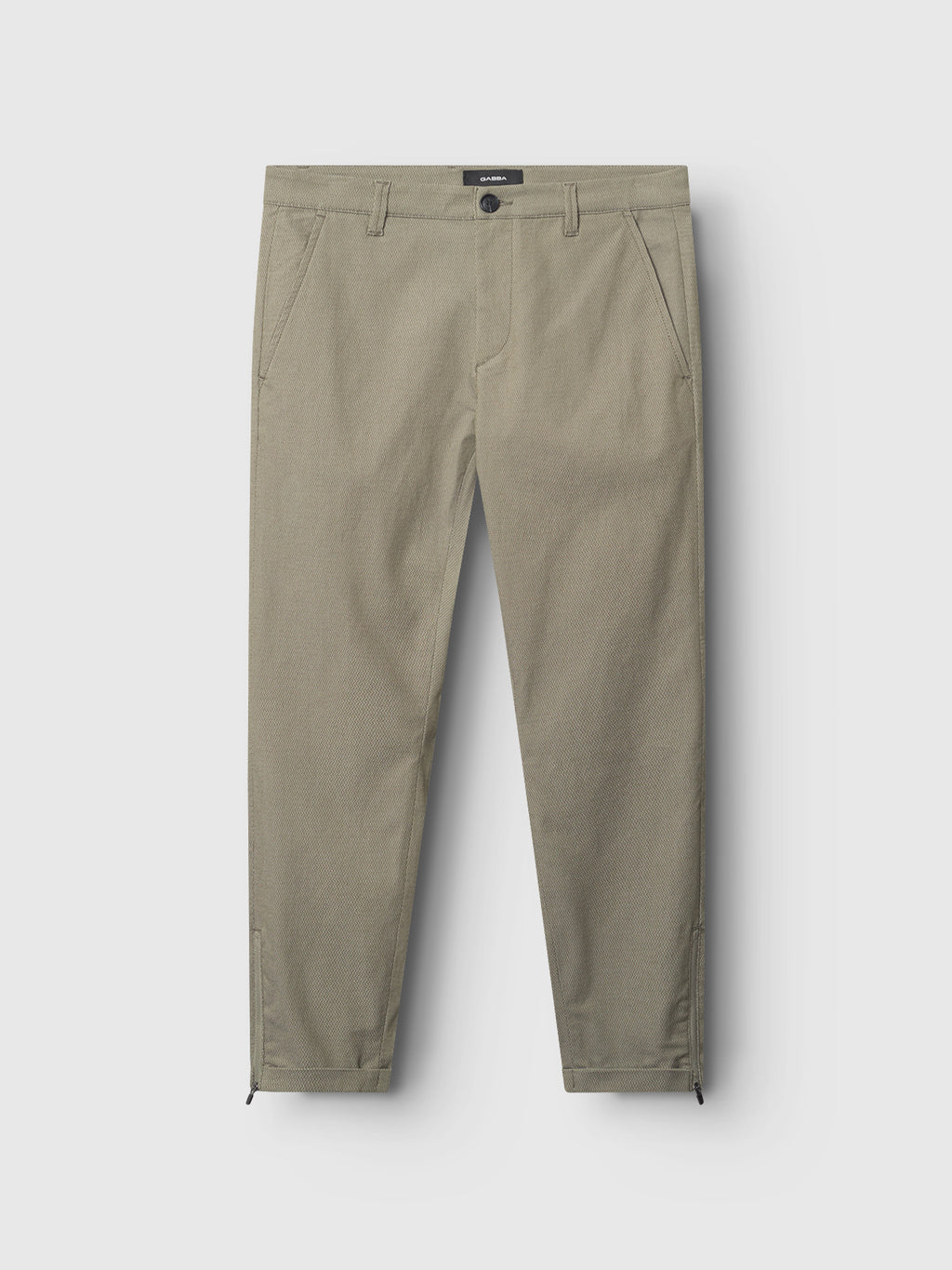 The Pisa K3280 Dale Pants by Gabba are olive green, slim-fit modern city pants made from high-stretch cotton-blend fabric. They feature side pockets, visible stitching, and Gabba Pisa zippers at the ankle cuffs, plus belt loops and a button closure against a light gray background.