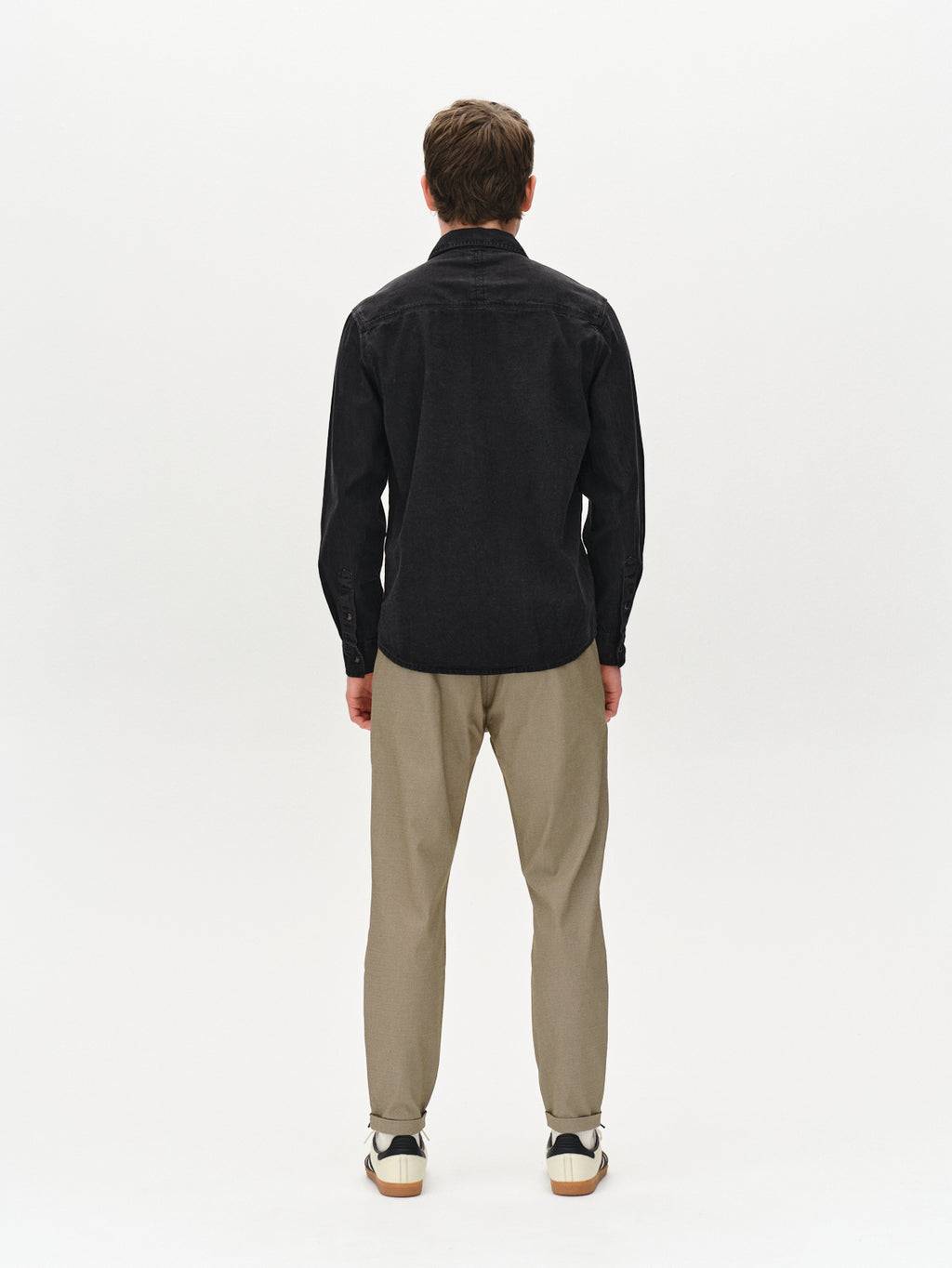 Rear view of a person in a black long-sleeve shirt and Gabbas Pisa K3280 Dale Pants in olive green, made from high-stretch cotton-blend fabric, with white sneakers featuring black accents, standing against a plain white background.