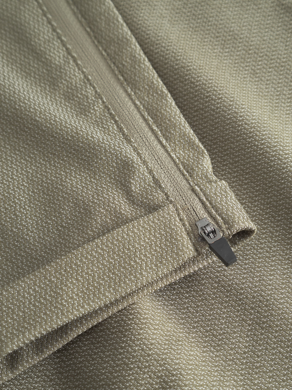 Close-up of an olive green fabric from Gabbas Pisa K3280 Dale Pants showcasing a high-stretch cotton-blend with a subtle woven texture. The partially open zipper reveals the folded edge, emphasizing detail and stitching in this modern city pant.