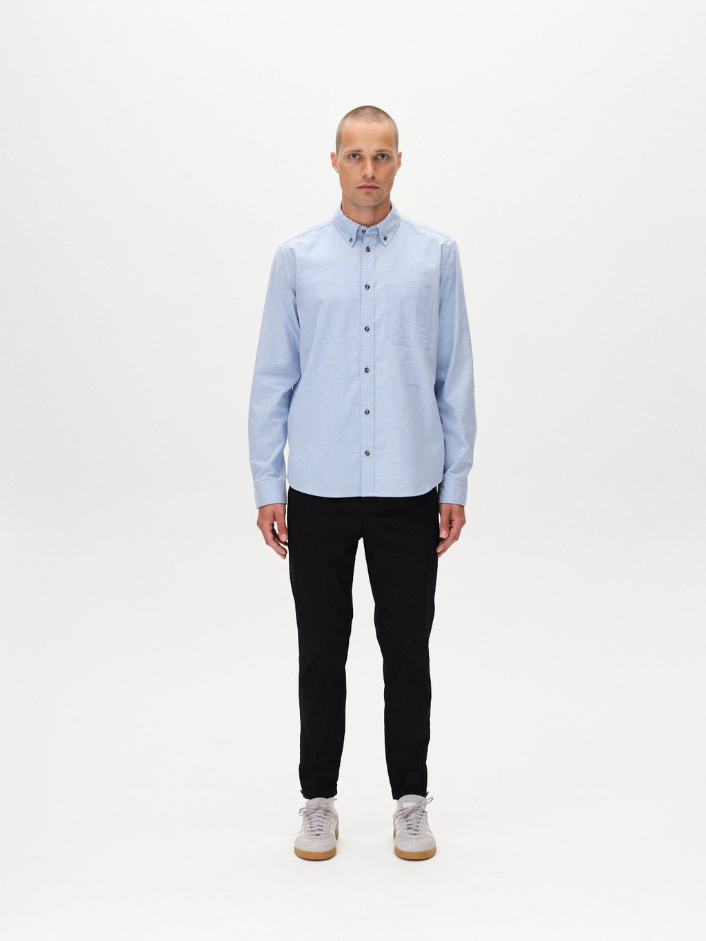 A person with short hair stands against a plain white background wearing a light blue button-up shirt, Gabba Pisa K3280 Dale Pants in black with a tapered fit, and light gray sneakers. They face forward with a neutral expression.