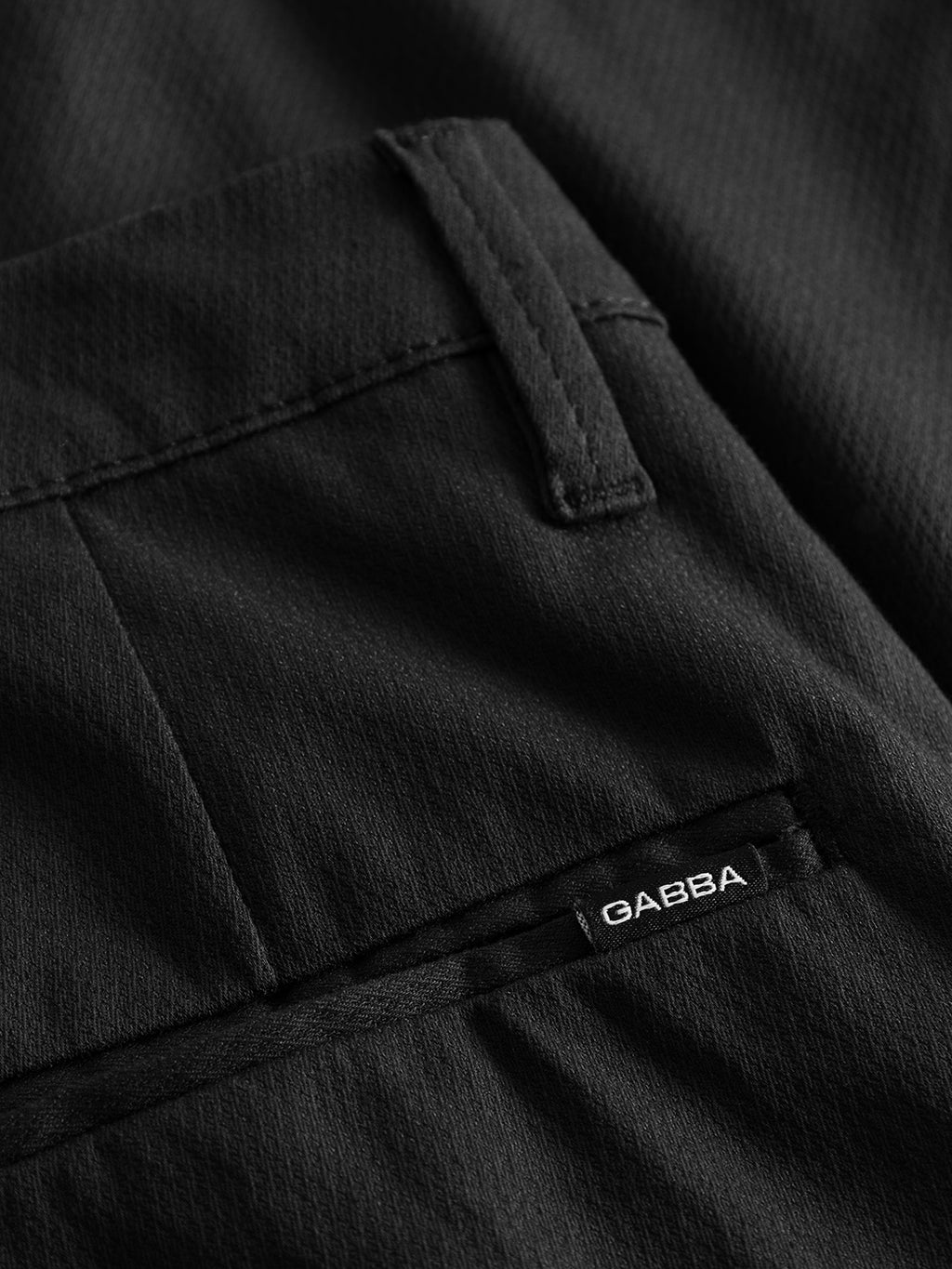 Close-up of Pisa K3280 Dale Pants - Black by Gabba: a modern city pant in high-stretch cotton-blend featuring neatly stitched pocket with GABBA label on lower right, enhancing its textured look and tapered fit.