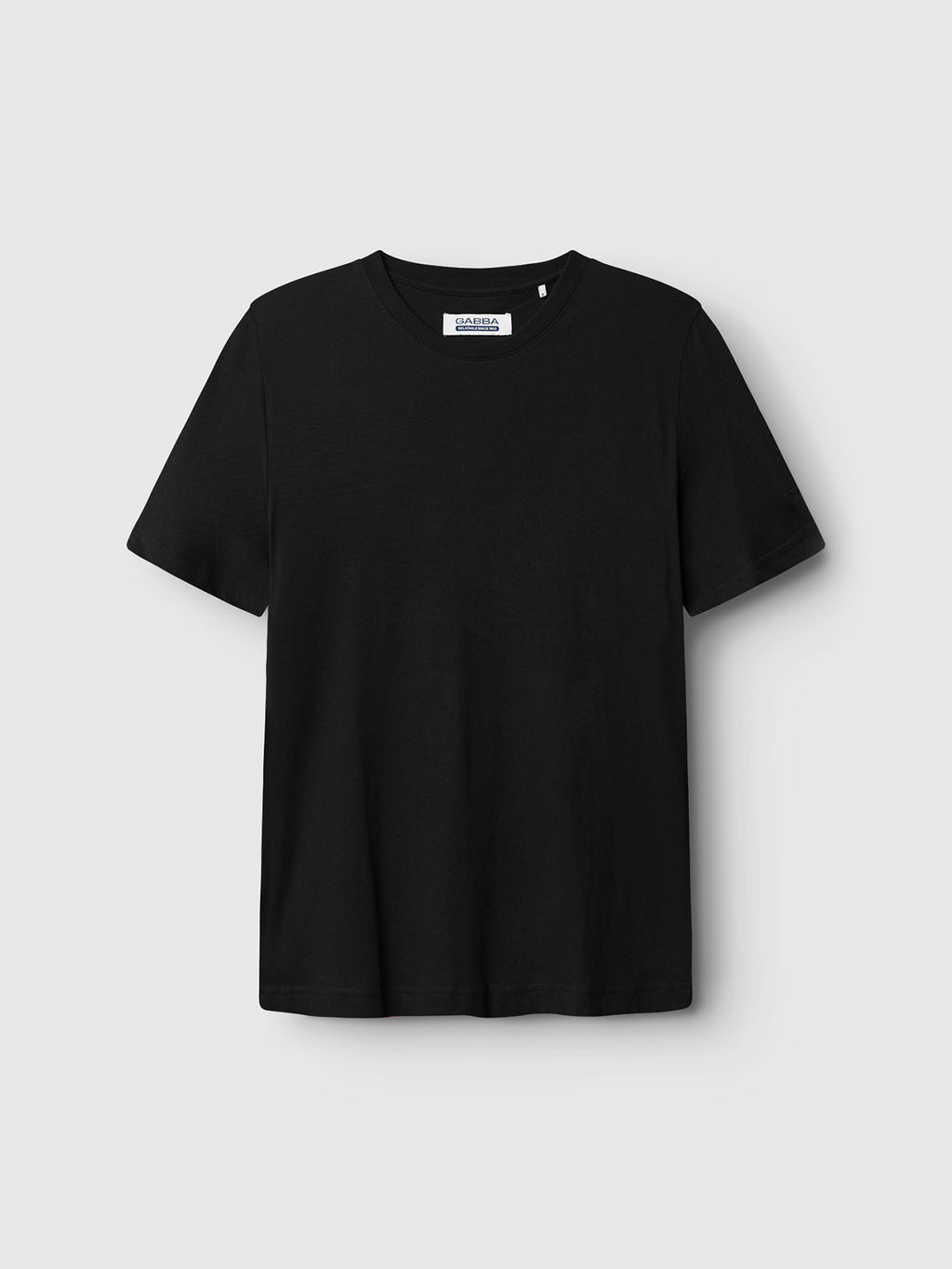 The Dune SS GOTS Tee by Gabba is a plain black T-shirt made from organic cotton, featuring short sleeves against a light gray background. It has a classic fit and a visible tag at the neckline.