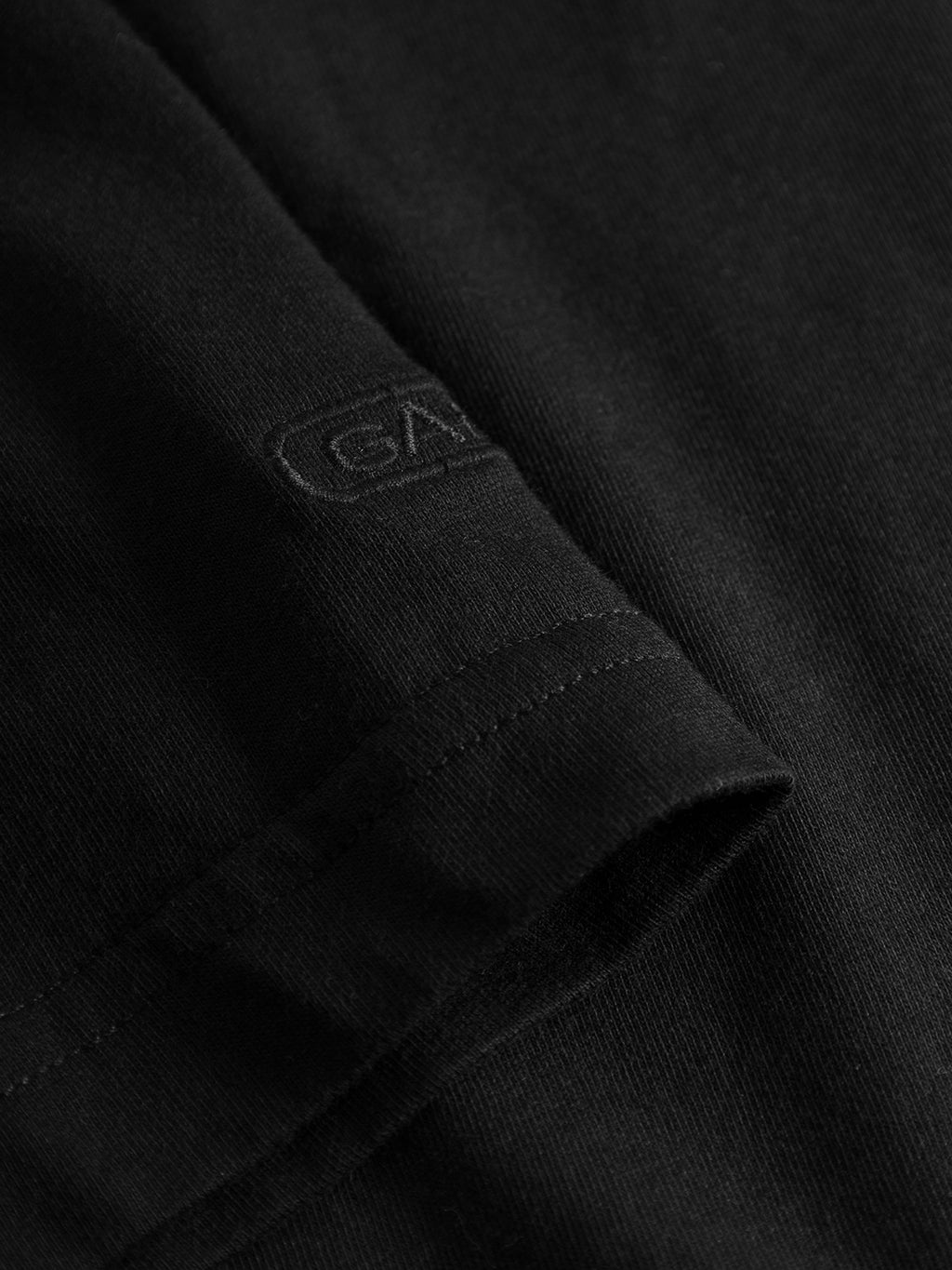 Close-up of Gabbas Dune SS GOTS Tee in black, featuring a visible seam and subtly embroidered logo. Made from GOTS-certified organic cotton, it offers a smooth texture with a slightly raised logo stitch that blends seamlessly.