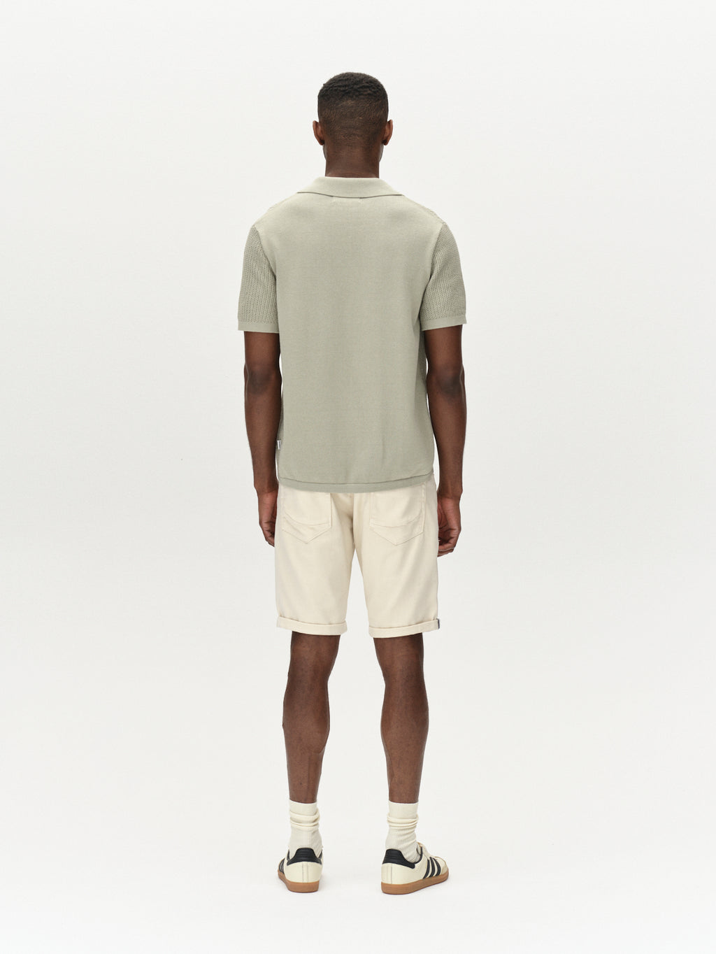 A person in a light green short-sleeved shirt and Gabbas Jason K3995 SANZA Shorts in Birch stands facing away against a plain white background, wearing off-white socks and sneakers with black stripes.