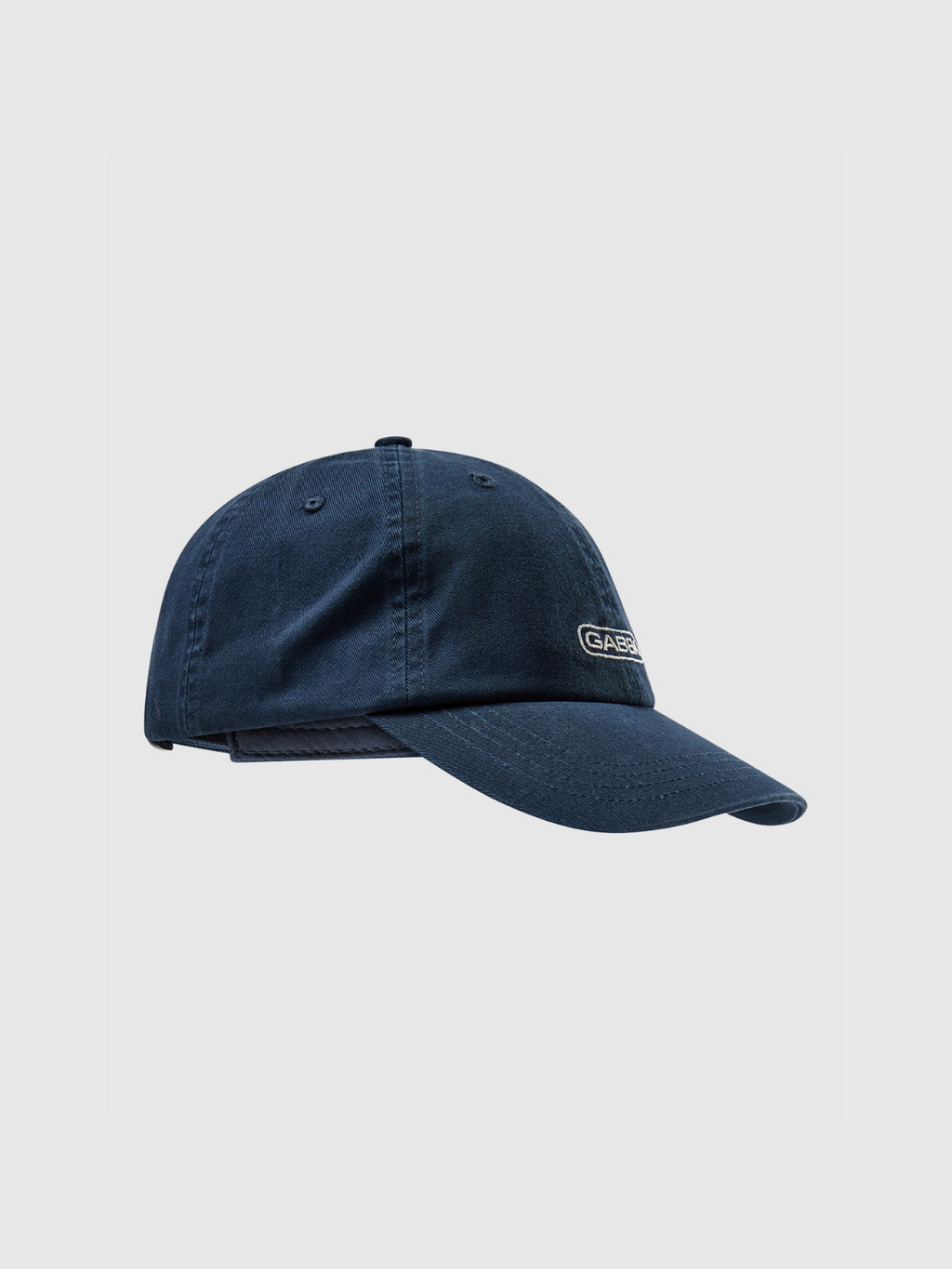 The Gabba Cap - Navy Blazer by Gabba features a stylish navy design, curved brim, and a small rectangular logo patch on the front, blending classic and modern looks. Photographed against a plain light gray background.