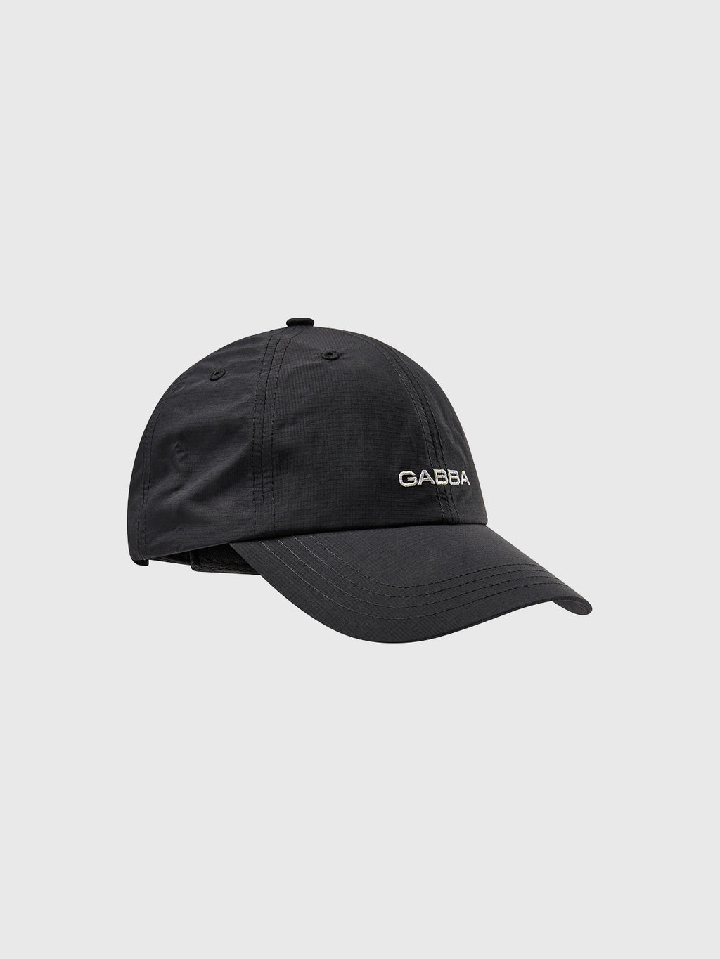 The Gabba Ribstop Cap - Black features a curved brim and GABBA embroidered in white on the front. This classic design offers a comfortable fit with its structured form, set against a plain gray background.