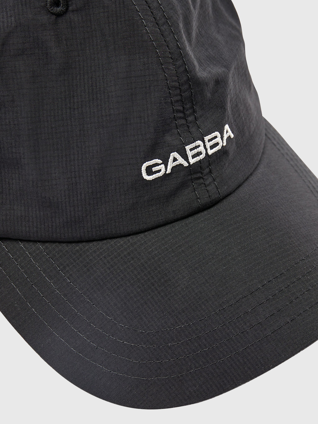 A close-up of the Gabba Ribstop Cap - Black shows GABBA embroidered in white on the front. Its subtly textured fabric and visible stitching highlight its curved brim and crown, ensuring a comfortable fit.