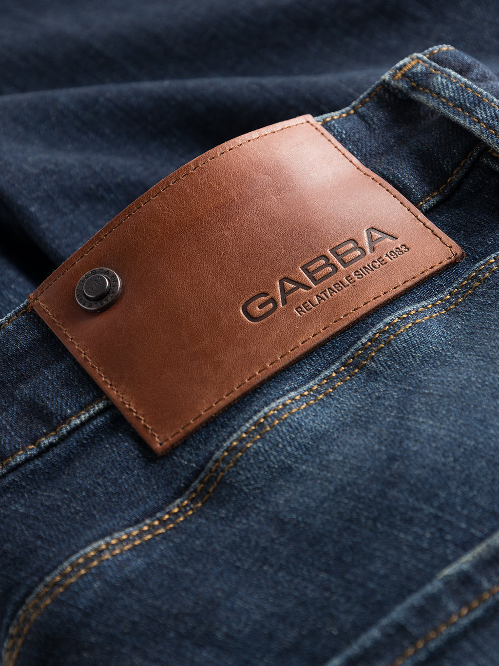 A close-up shows a pair of Gabba Rey K4441 mid-blue denim jeans, featuring a brown leather patch on the waistband embossed with GABBA and RELATABLE SINCE 1983, with detailed stitching adding to their laid-back look.