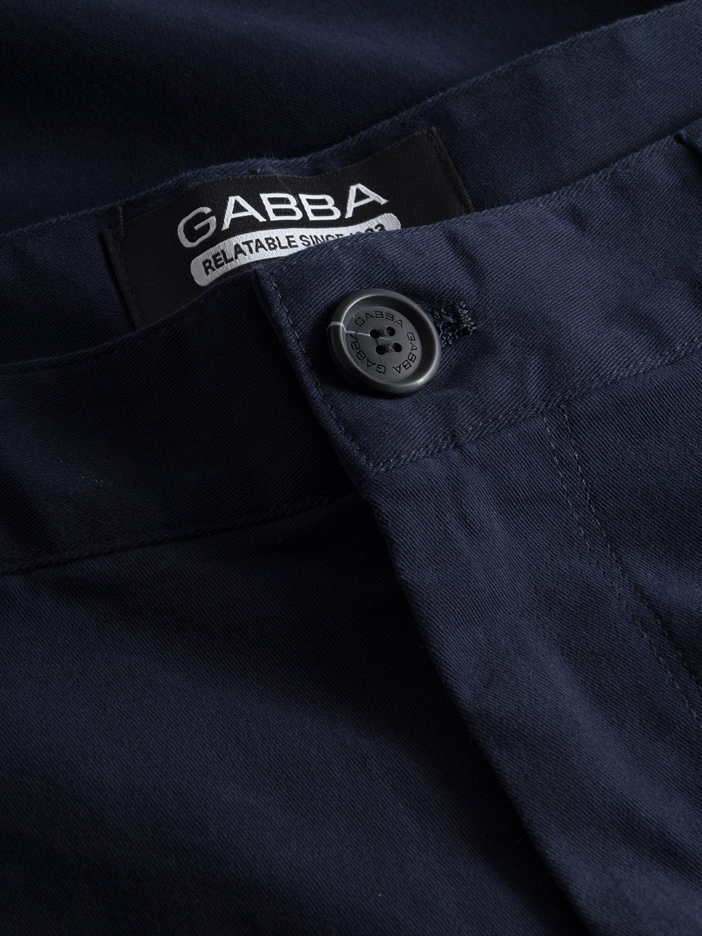 Close-up of Venza Chino - Navy pants with button closure. Inside, a label reads Gabba and Reliable since 1983, making it a staple for any mens wardrobe.
