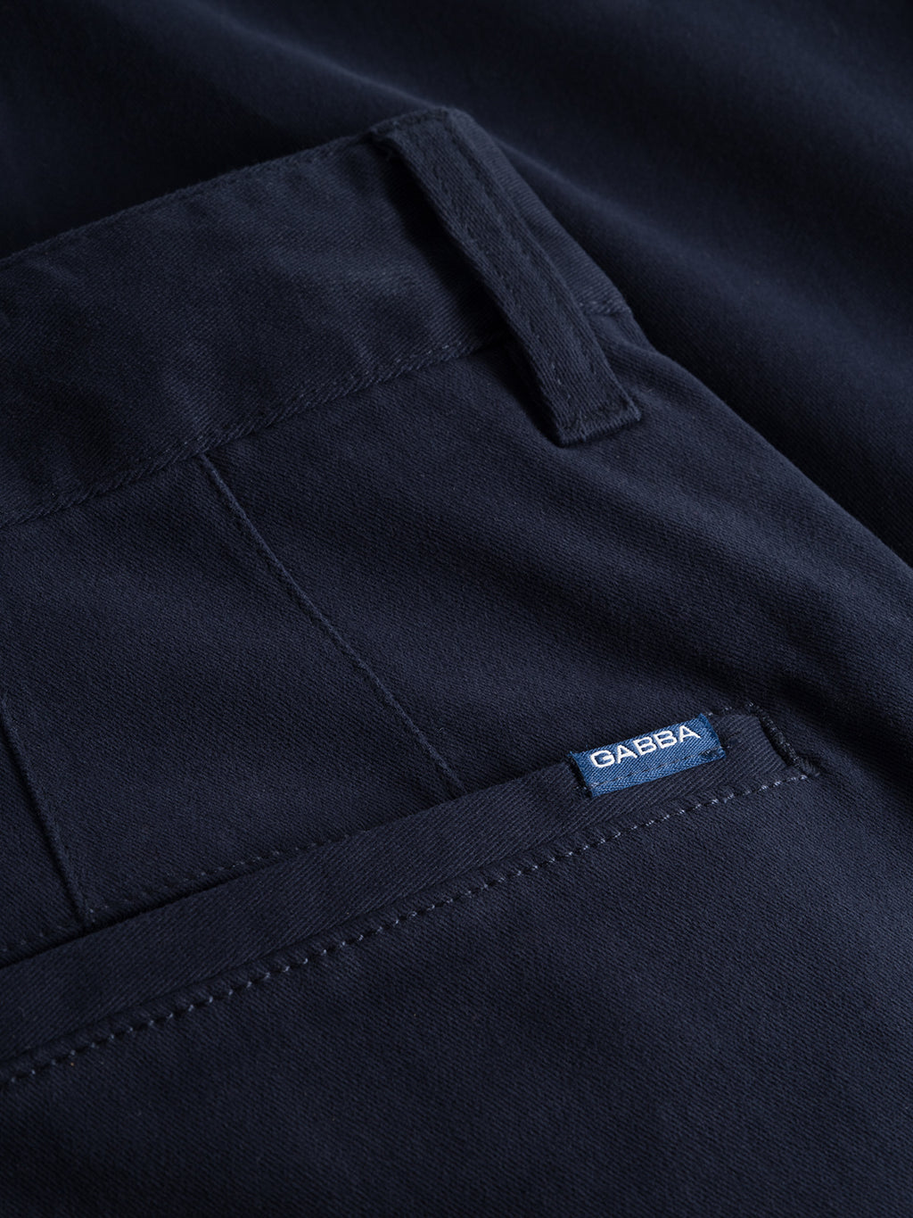 Close-up of the Venza Chino - Navy by Gabba, highlighting the fabrics details like the back pocket and belt loops. A small blue tag on the pocket adds distinction, while visible stitching showcases craftsmanship, making it a wardrobe staple.