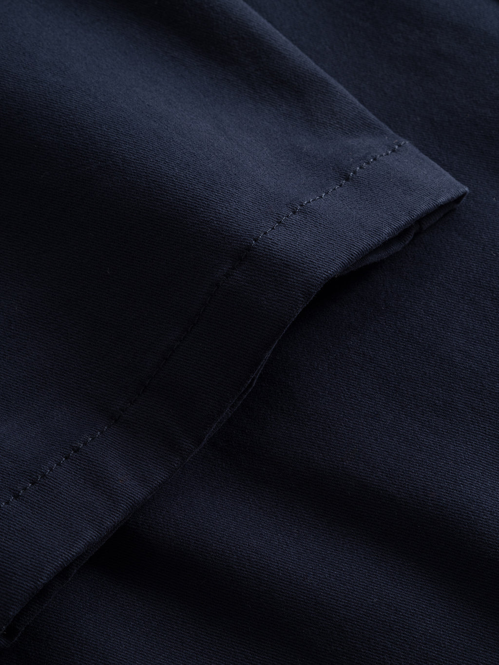 A close-up of the Venza Chino - Navy by Gabba highlights the detailed stitching on the hem. The smooth fabric and deep navy shade subtly contrast with the seams, embodying classic sophistication in a mens wardrobe.