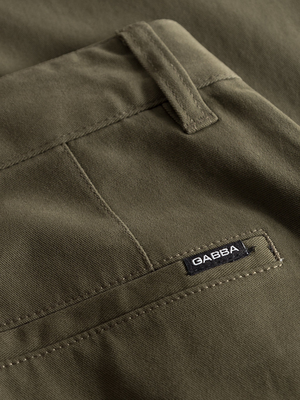 Close-up of the olive green Venza Chino from Gabbas mens collection, highlighting a smooth, well-stitched fabric with a back pocket, a small GABBA label, and a belt loop above it, emphasizing its regular fit design.