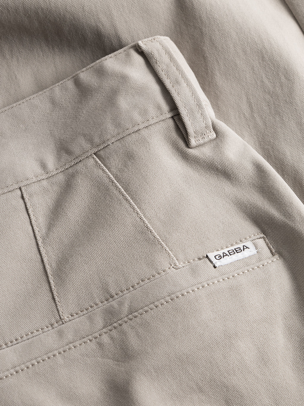 Close-up of the Venza Chino in Lt. Sand, featuring a Gabba label on the pocket. The fabric texture and belt loop are visible, making it an essential piece for any mans wardrobe.
