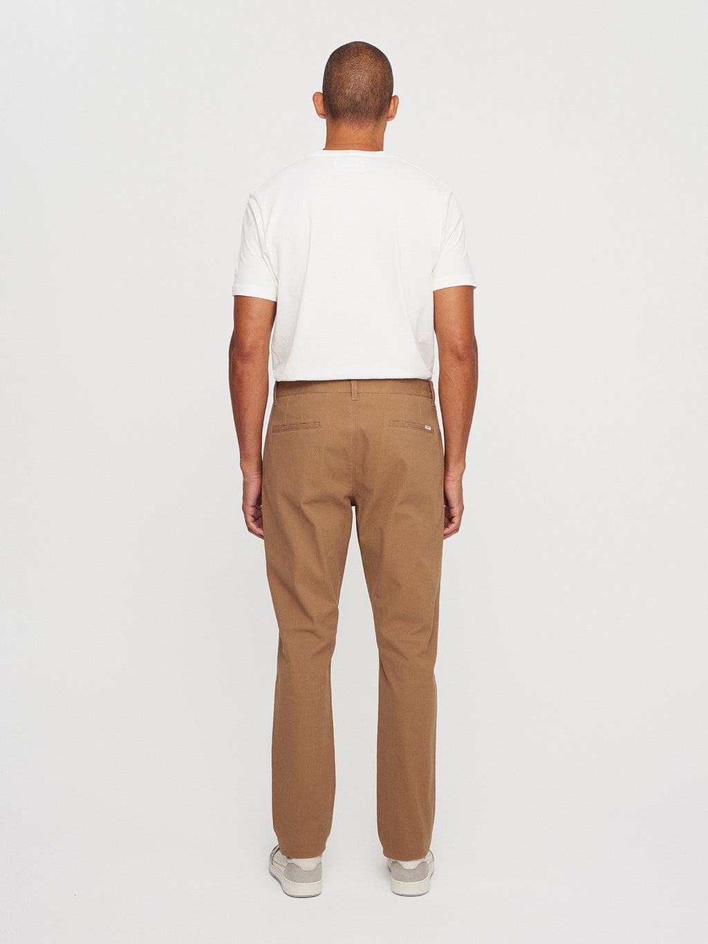 A person is shown from behind against a plain white background, wearing a Gabba Venza Chino in Lt. Brown, paired with a white T-shirt and beige shoes—essentials for any mens wardrobe.
