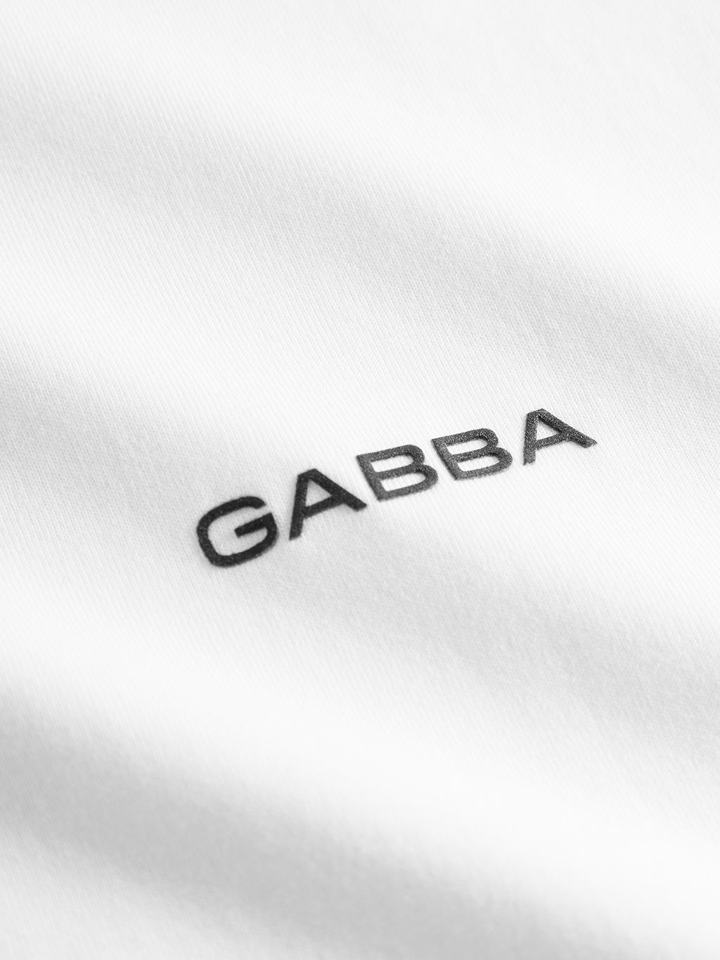 Close-up of Gabba Dune Logo SS GOTS - White: organic cotton fabric with GABBA embroidered in black uppercase letters—ideal for a classic fit t-shirt.