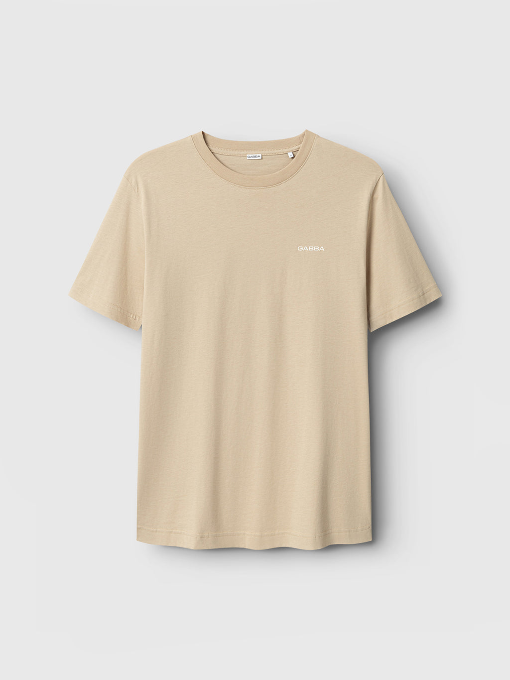 The Gabba Dune Logo SS GOTS - Safari is a beige organic cotton t-shirt with short sleeves, a round neckline, and a small white Gabba logo on the left chest, shown against a light gray background.