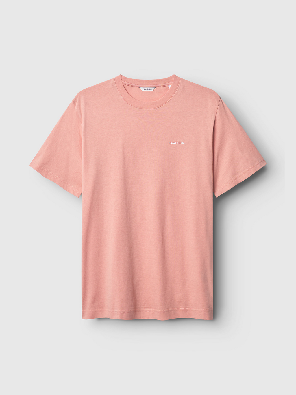 The Gabba GABDune Logo SS GOTS in Rose Peach is a basic, short-sleeved light pink T-shirt featuring a small white logo on the chest, shown against a light gray background.