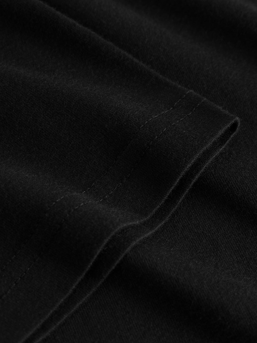 Close-up of the hem on Gabbas Dune Logo SS GOTS t-shirt in black, highlighting detailed stitching and inviting texture.