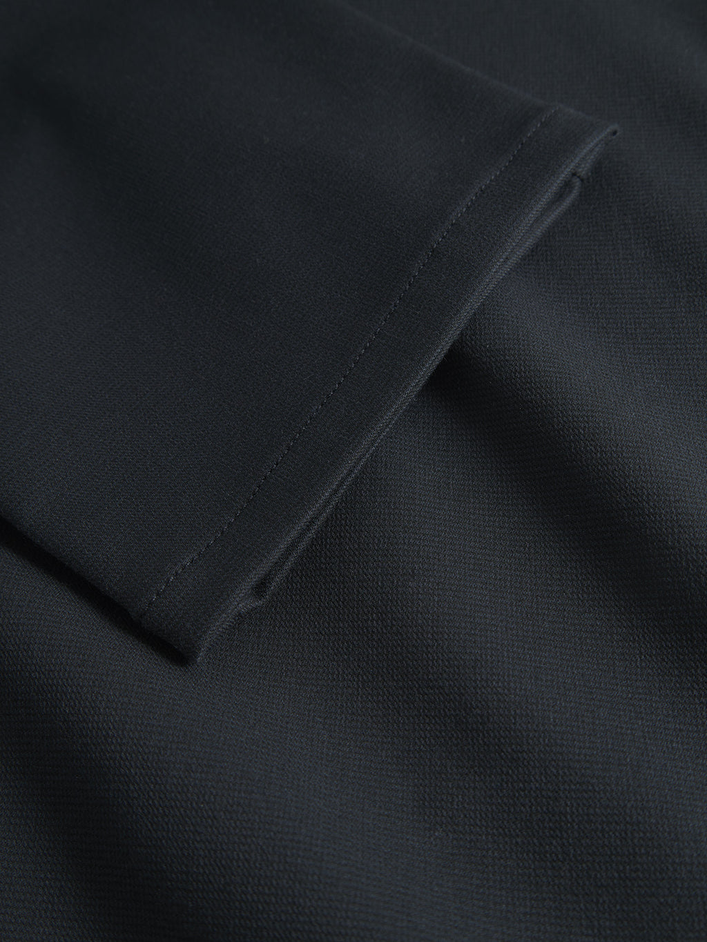 Close-up of Paul Domo from Gabba in Navy Mel., featuring dark fabric with French pockets, visible stitching, and folded seam. The tightly woven material has a smooth texture and subtle sheen, reminiscent of finely crafted slim chino pants.