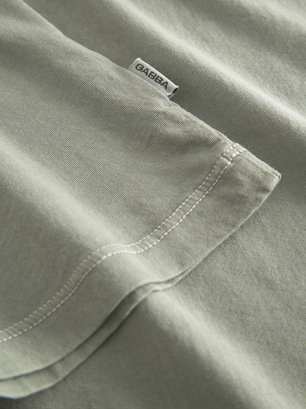 A close-up of the Lagos SS - Green Sea t-shirt highlights its light green color and visible stitching. Featuring a classic fit with a comfortable round neckline, the shirt has a small GABBA tag near the top edge, showcasing its quality and texture.