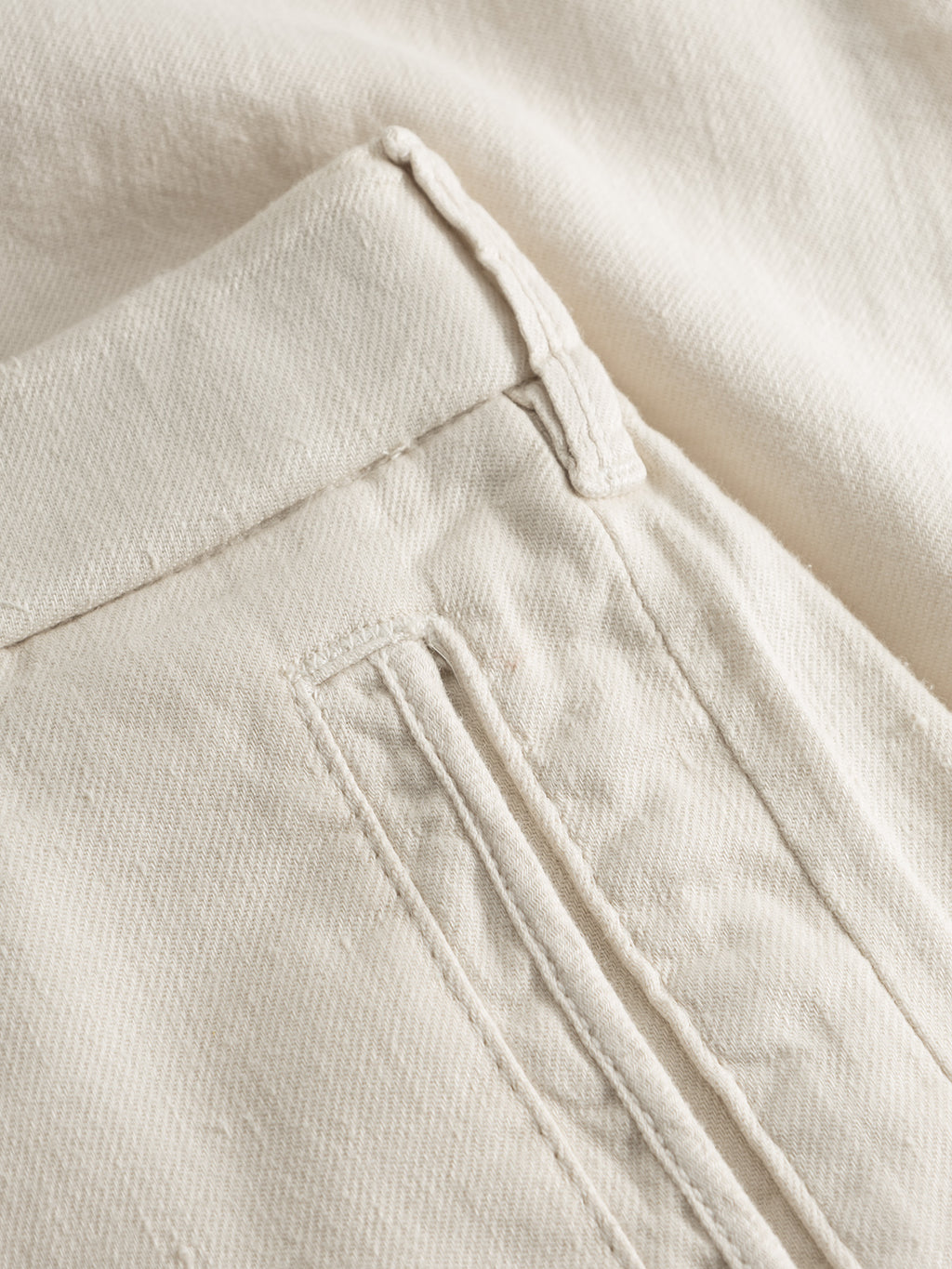 Close-up of beige fabric featuring a neatly sewn pocket typical of Gabbas Napoli 19 Twill Linen - Birch pants. The material has a subtle weave, with even and precise stitching for a clean, minimalist look focused on comfort.