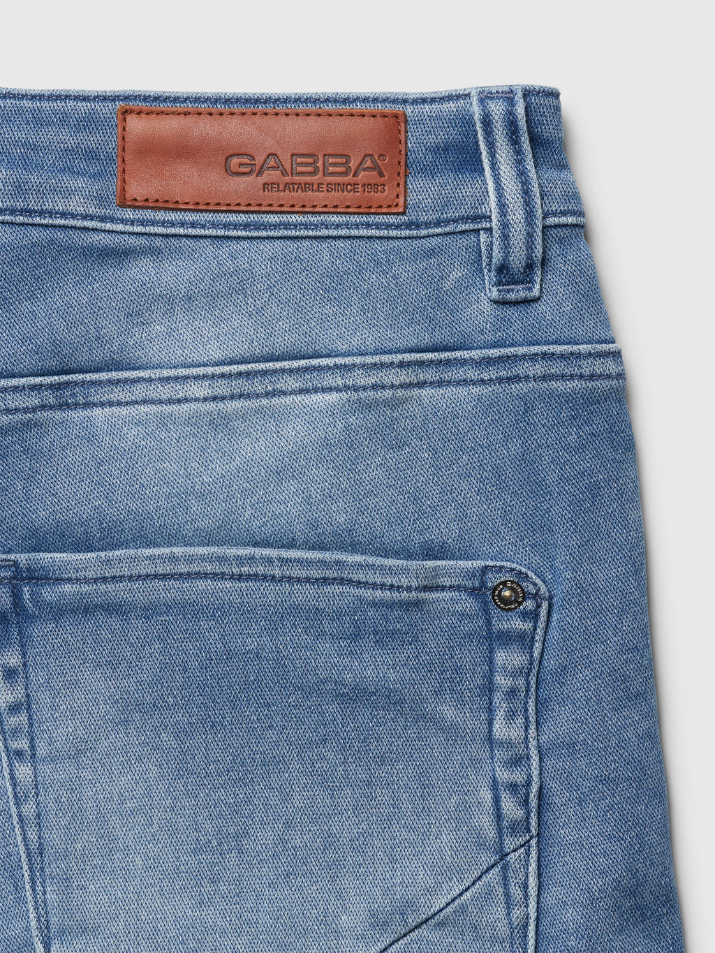 Close-up of Jason K3787 SANZA Shorts in light blue denim by Gabba, showing the back pocket and a brown leather patch on the waistband embossed with GABBA and RELATABLE SINCE 1983. Made from super-stretch fabric for optimum comfort.