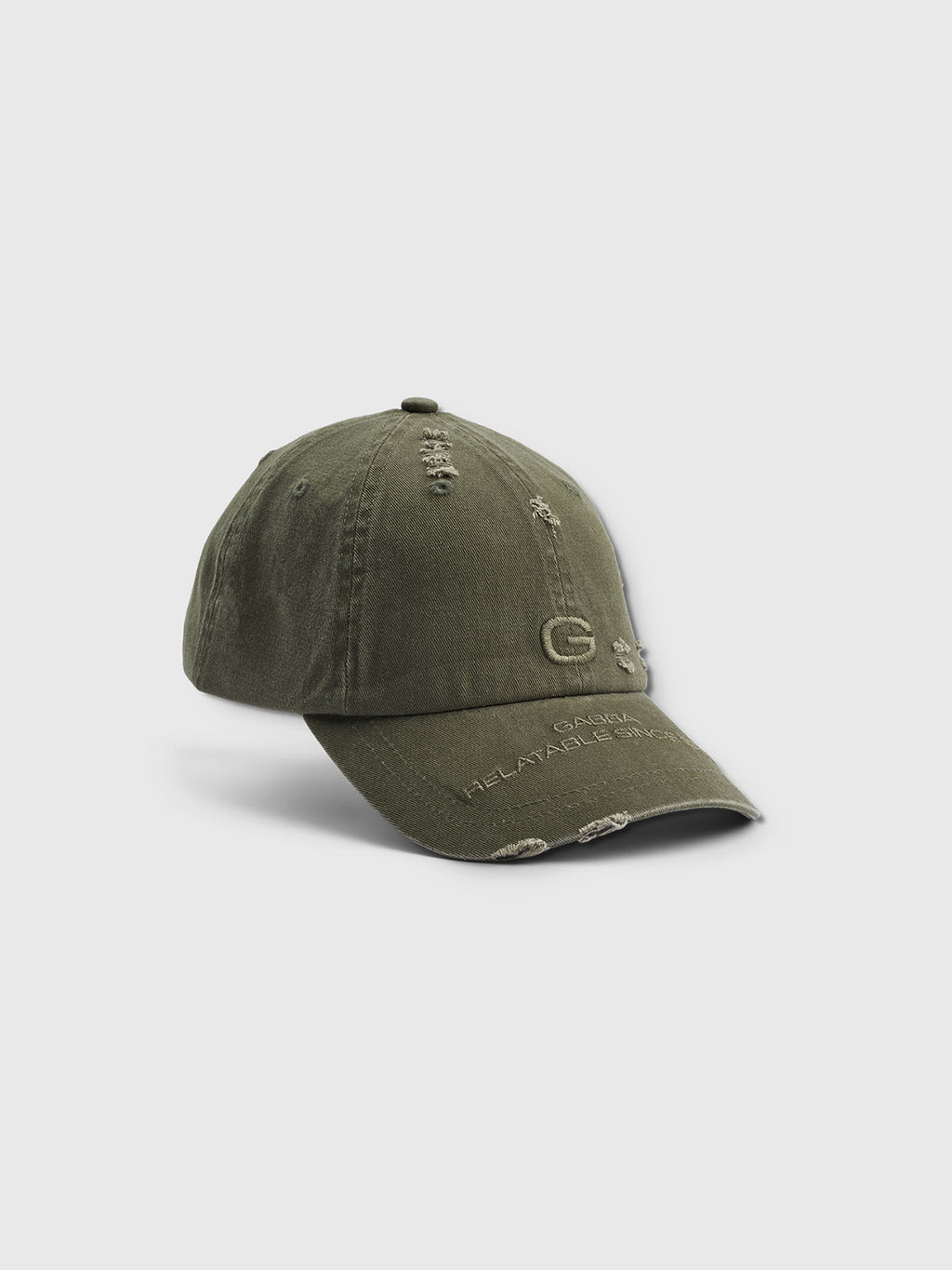 The Dad - Army cap by Gabba is an olive green cotton baseball cap with a prominent embroidered G on the front. It features slight distressing, visible stitching, a curved brim, and ensures comfort with a soft gray background.