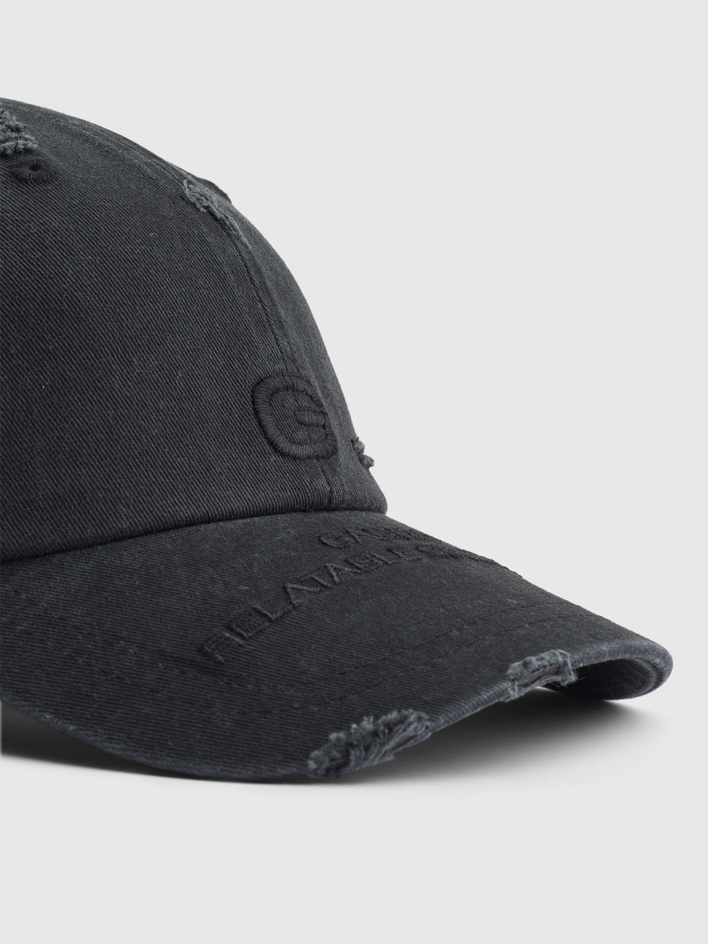 A close-up of Gabbas stylish Dad - Meteorite black distressed baseball cap, made from comfortable cotton. It features minimal front embroidery with slightly frayed edges and visible stitching against a plain light grey background.