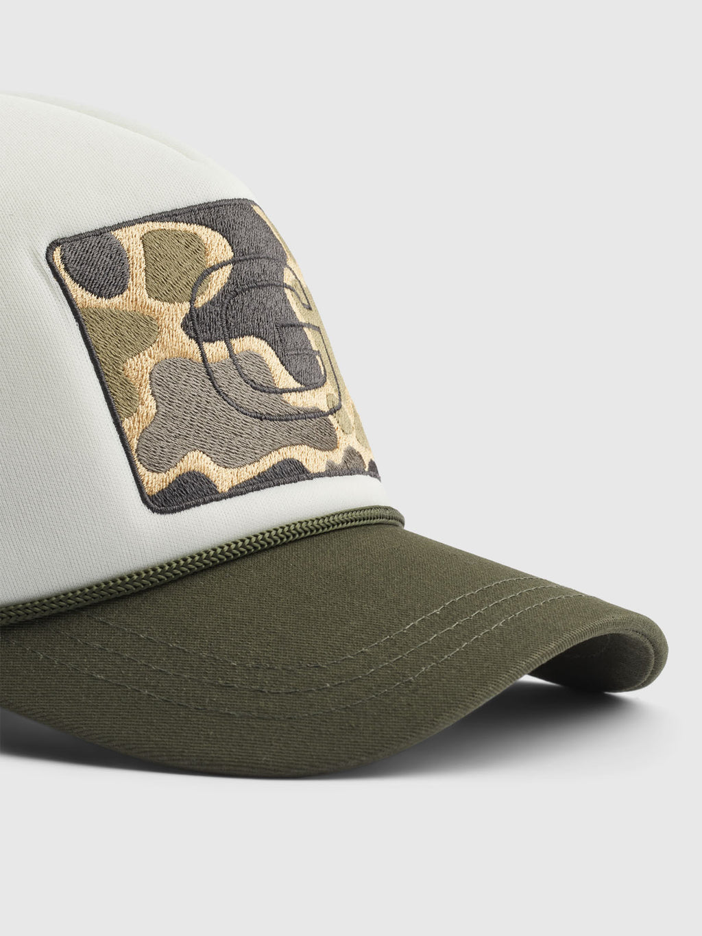 The Wolf Cam - Army baseball cap by Gabba features an olive green visor, a white front panel with a camouflage embroidered patch and stylized black Gabba helmet logo, complemented by an adjustable strap, against a light gray background.