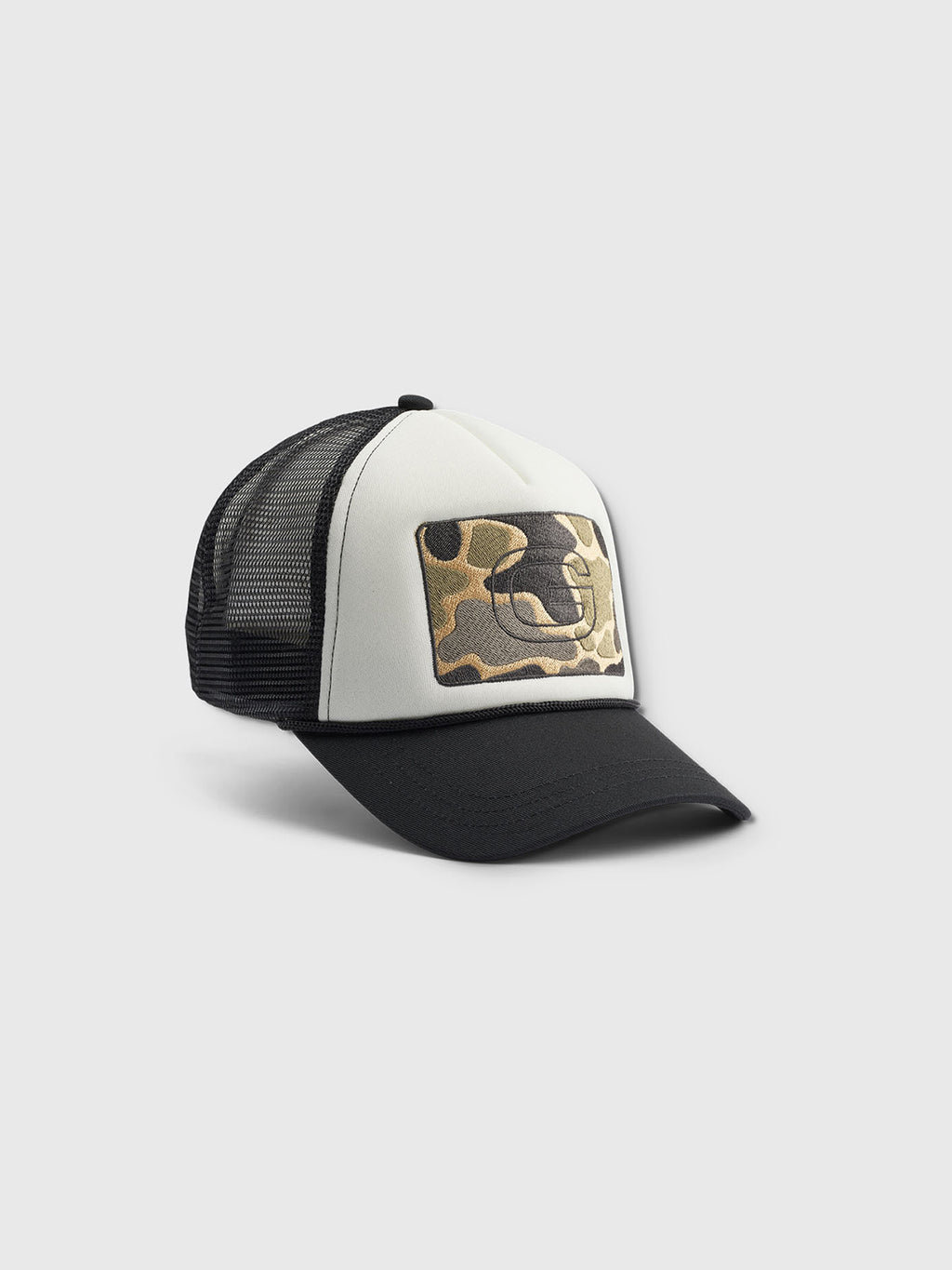The Gabba Wolf Cam - Meteorite trucker cap features a black mesh back, white front panel, camo-pattern patch with the Gabba logo, adjustable strap for comfort, and a contrasting black brim against a light gray background.