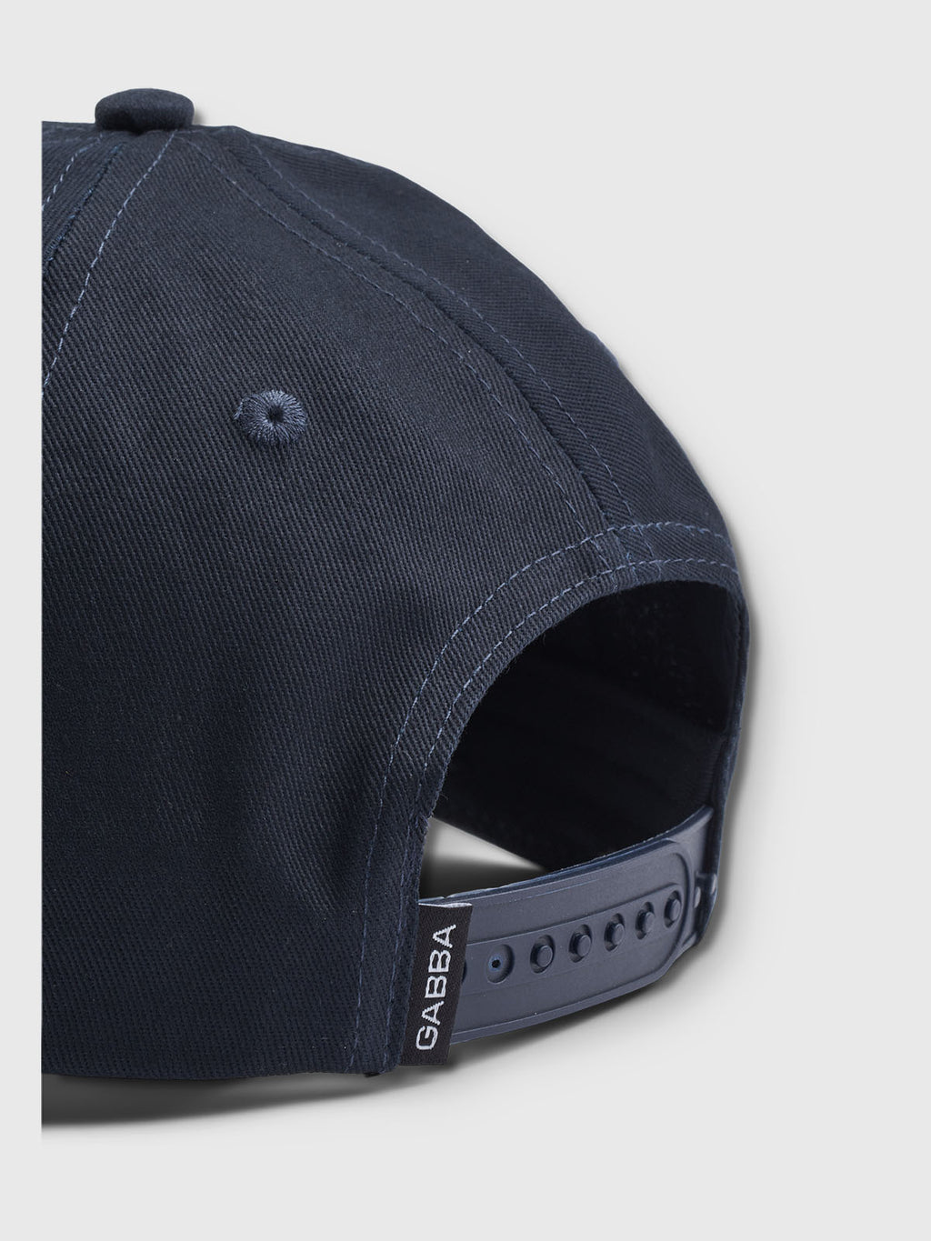 The Gabba Base - Navy cap features a modern design with an adjustable strap and small GABBA label. Its made of smooth fabric with a top button, shown from the back against a light gray background to highlight its classic fit.