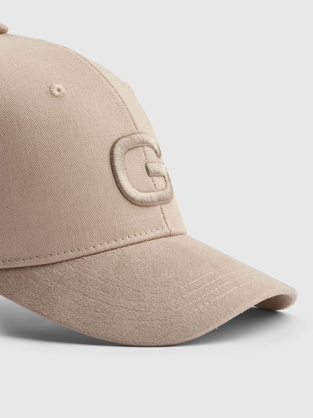 Gabba presents the Base - Sand cap, showcasing a raised, stitched letter G on the front. With a classic fit and modern design elements, it features soft texture and visible stitching along the brim and panels. The cap is angled to the right against a light background.
