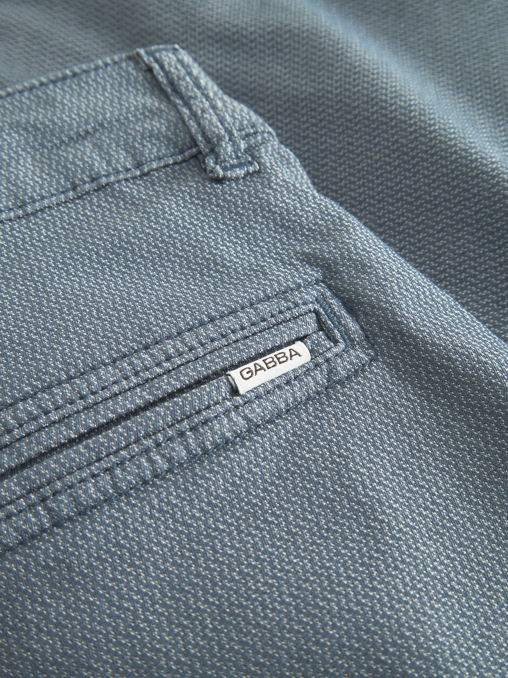 Close-up of the Jet K3280 Dale Shorts by Gabba in blue, featuring a textured fabric with a subtle dotted pattern. A small pocket showcases detailed stitching and a sewn GABBA label, enhancing its timeless appeal and comfortable fit.