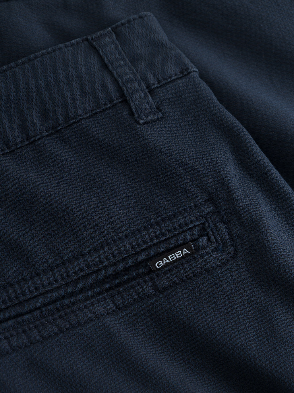 The navy Jet K3280 Dale Shorts by Gabba feature a close-up of fabric with a back pocket, showcasing a small stitched Gabba brand label. The pocket has a modern design with a horizontal zipper beneath the belt loop, and the fabric offers subtle texture for all-day comfort.