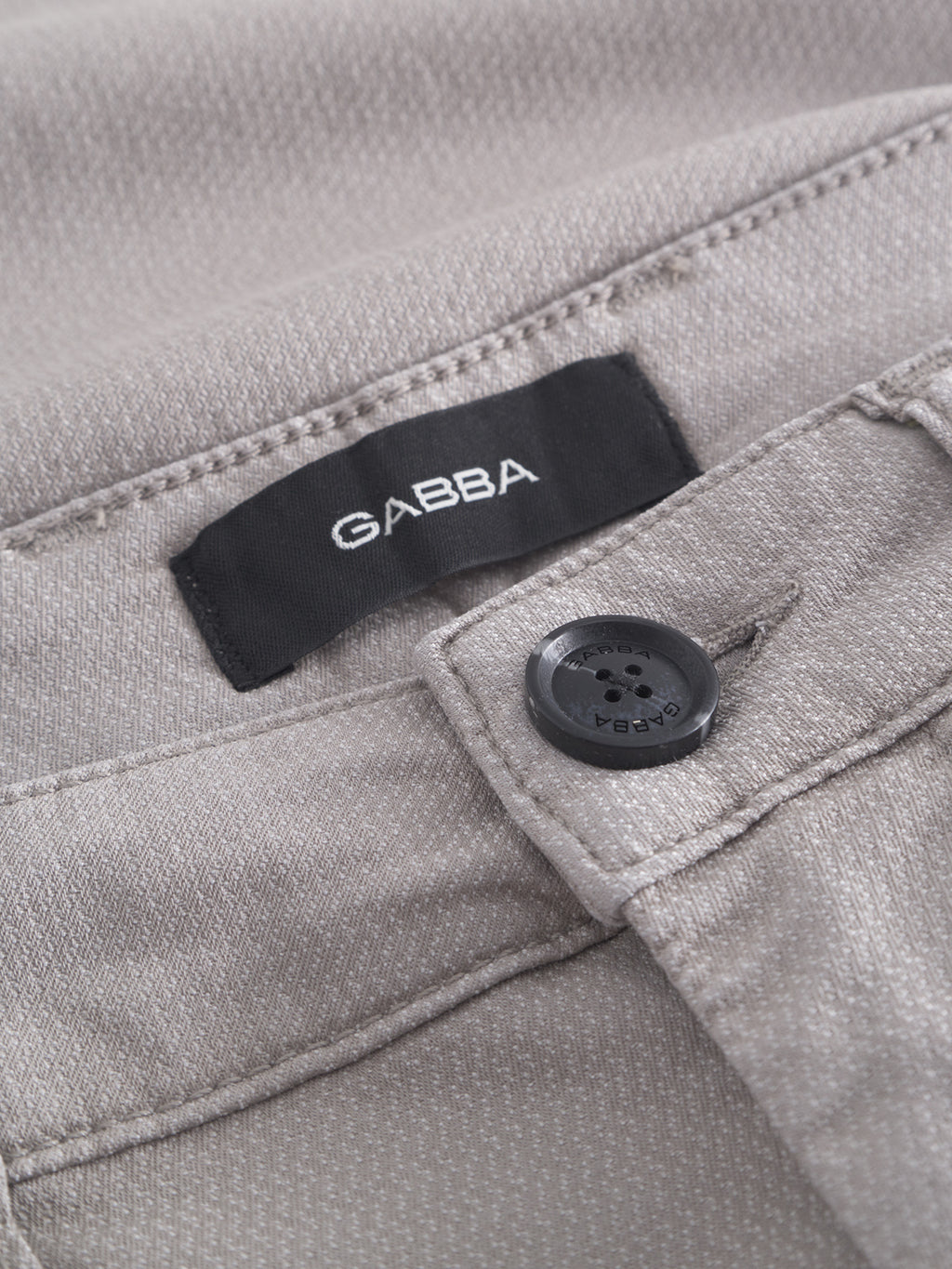 A close-up of the Jet K3280 Dale Shorts in Grey Paloma features a black label with Gabba inside the waistband. These shorts exude a timeless appeal with textured fabric for comfort and have a button engraved with Gabba near the label.