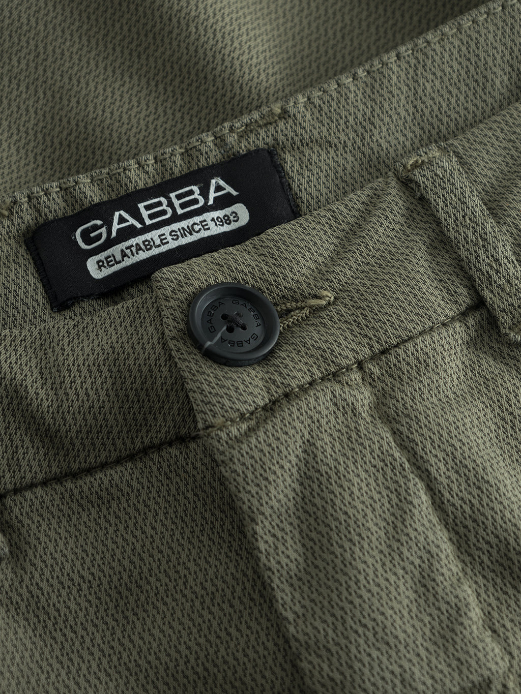 Close-up of the Deep Lichen Green Jet K3280 Dale Shorts made by Gabba, showcasing textured fabric with a black button and belt loop, exuding effortless style and featuring the label Gabba Relatable Since 1983..