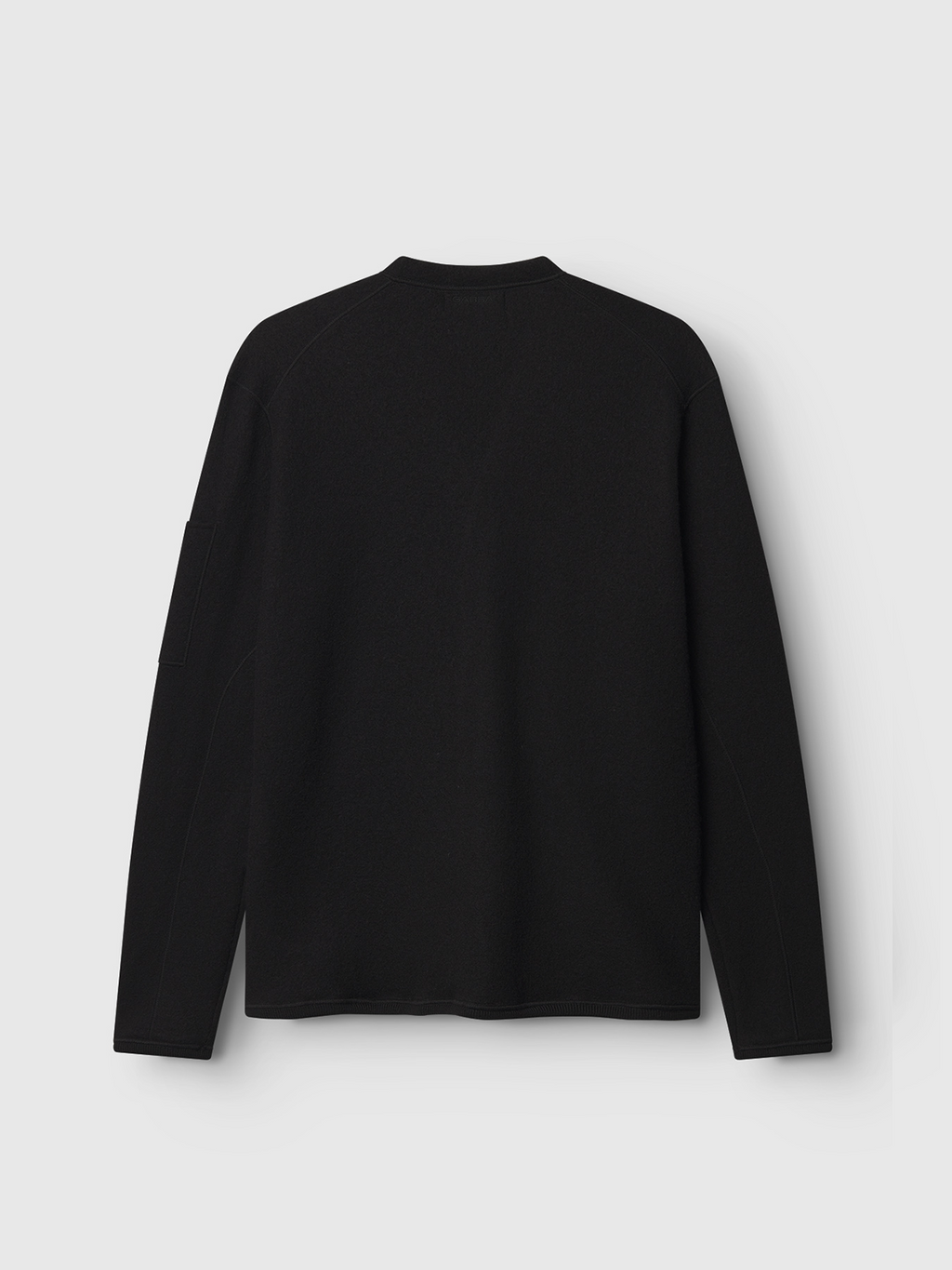 The Gabba Mattia Ls - Meteorite, a plain black long-sleeve with flatlock stitching, crew neckline, and soft fabric, is showcased against a light gray background with its back view visible in the image.