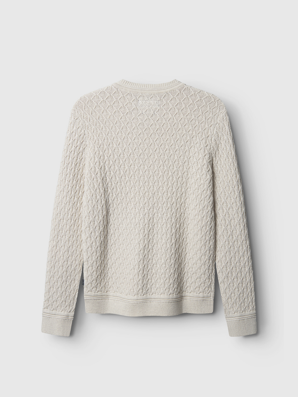The Aksla Ls - Egret by Gabba is a cream-colored, long-sleeved knitted sweater featuring a honeycomb and diamond pattern against a white background. Crafted from 100% cotton, it ensures superior comfort with ribbed cuffs and hem.