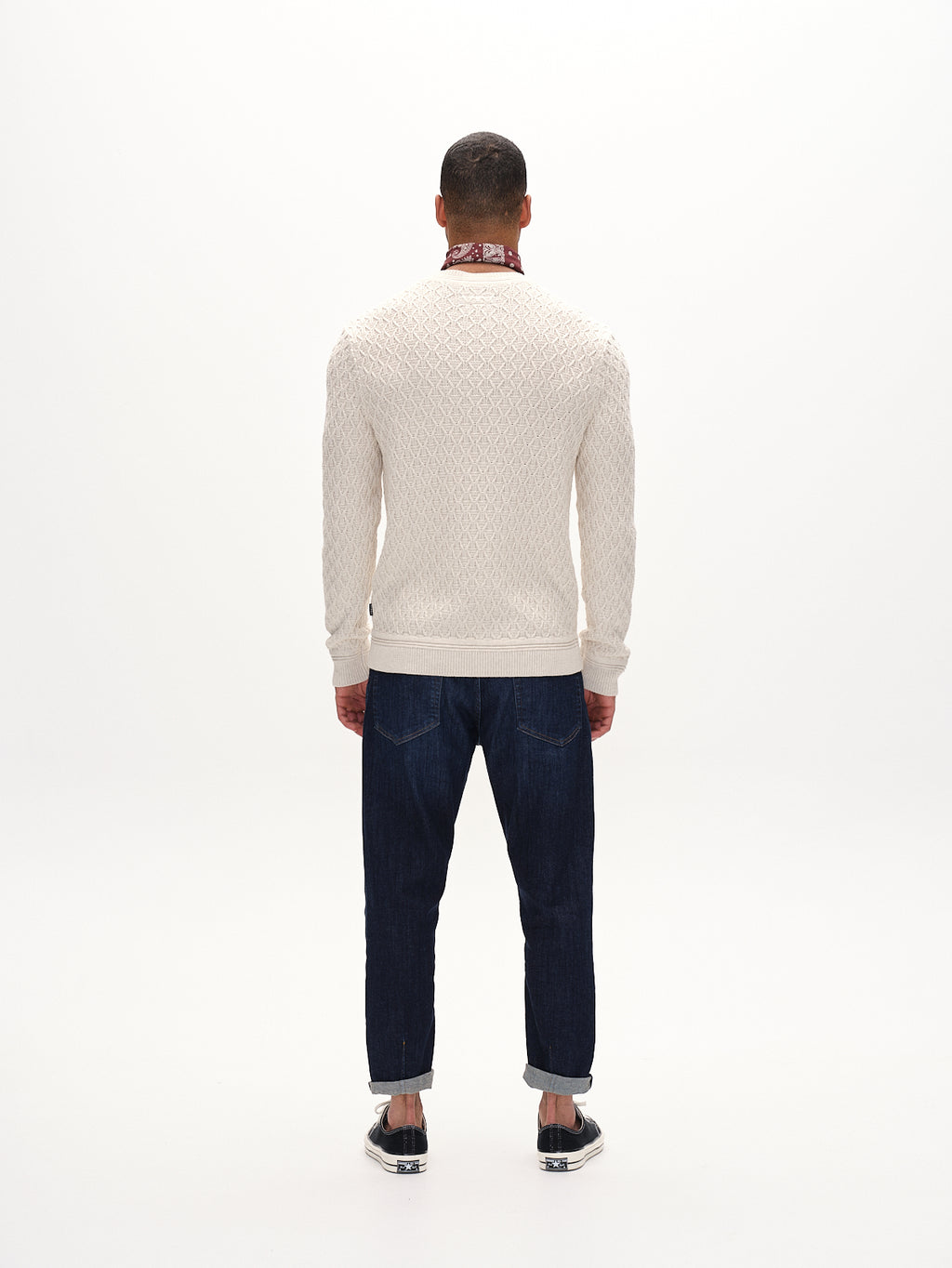 A person stands with their back to the camera wearing the Gabba Aksla Ls - Egret, dark jeans, and black shoes. They add a flair with a red bandana around their neck against a plain white background.