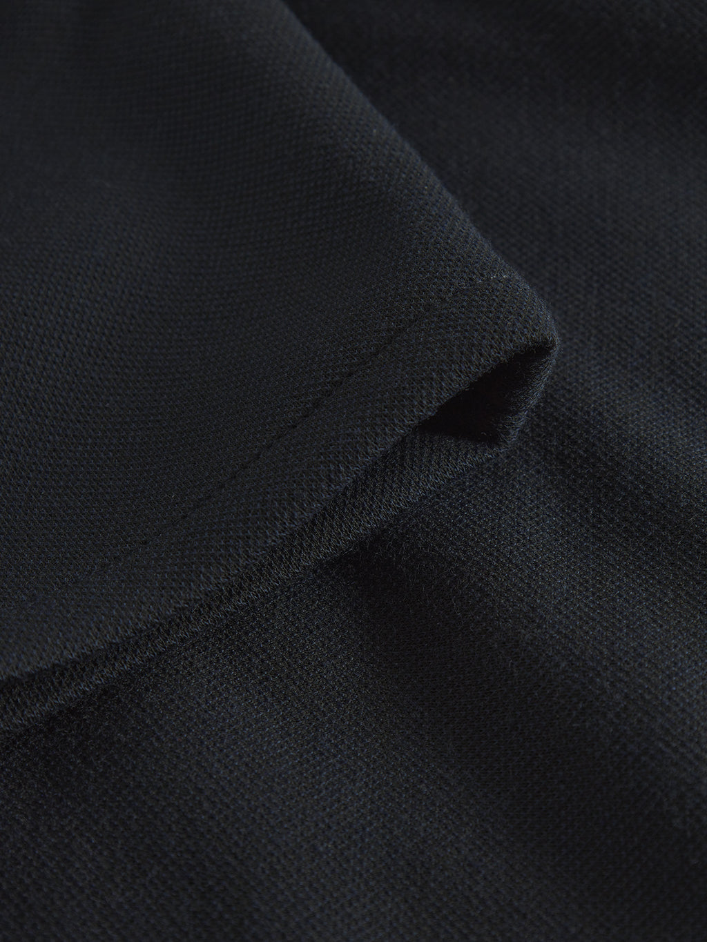 A close-up of navy fabric reveals a unique knitting technique from Gabba, giving it a soft, slightly ribbed texture with folds that add depth—a perfect material for Paul GKnit pants designed for everyday wear.