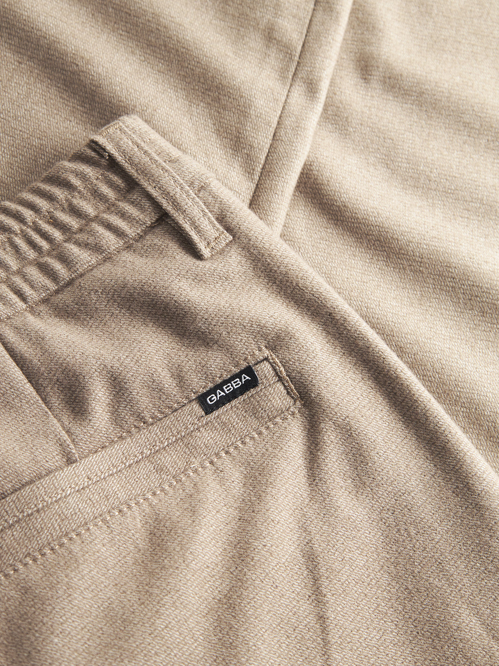 Close-up of Gabba’s Monza Shafi - Brown pants in beige brushed cotton with an elastic waistband, side seam, and pocket with a small black Gabba label. The fabric has a soft, wool-like texture.