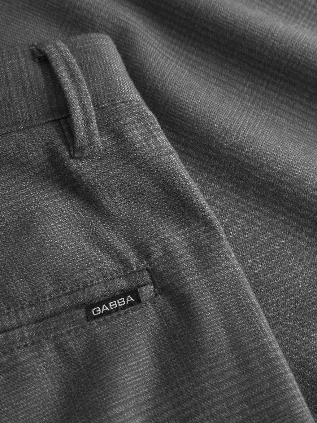 Close-up of Pisa Field - Grey pants from Gabba in metro style showcases gray textured fabric, part of the waistband, a belt loop, and a small black tag with GABBA in white near the pocket; made from high-stretch cotton-blend for comfort.