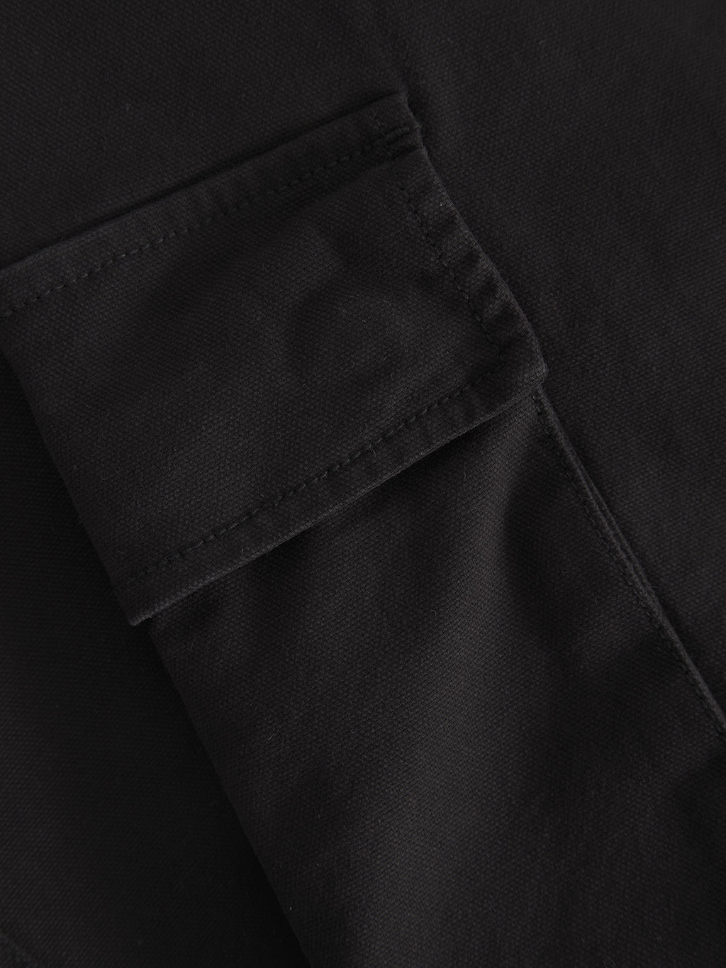 Close-up of the Gabba Verona Ent Poc - Meteorite, highlighting the black textured fabrics pocket with flap, stitching, folds, and garment dye finish.