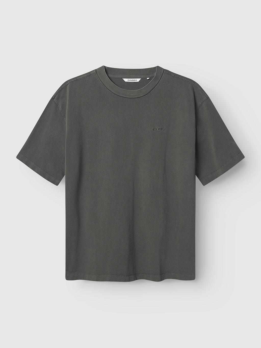 The Gabba Nigel Wix Boxy Hour SS t-shirt in washed dark grey features short sleeves, a crew neck, a relaxed modern fit, and a subtle chest logo, shown hanging against a light grey background.