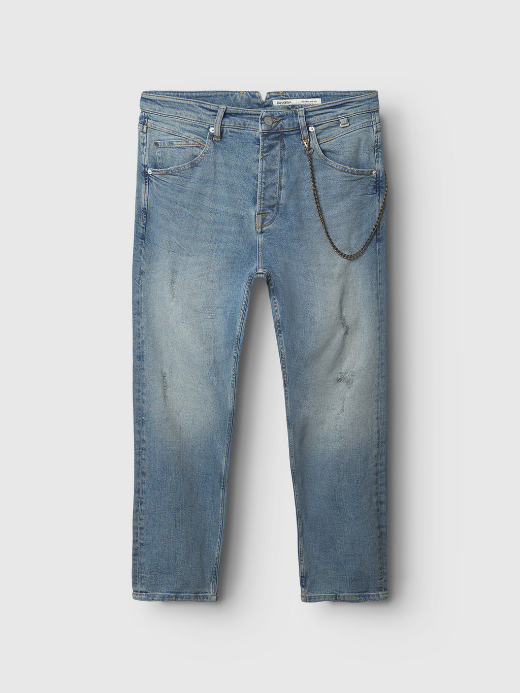 The Gabba Alex Cros Lt. Blue Denim jeans, made from recycled cotton, feature a distressed look with a metal chain on the right pocket. They have a classic five-pocket design and relaxed fit, hanging against a simple backdrop for an eco-friendly style.