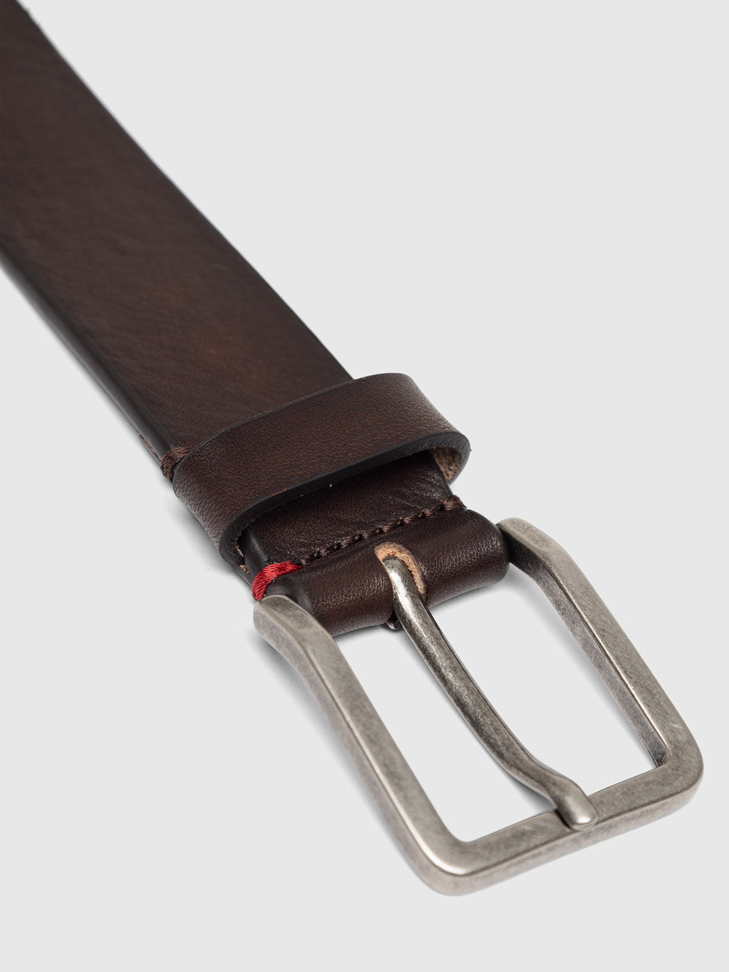Close-up of the Gabba Italy Belt - Brown, showcasing its elegant leather with a square silver buckle, loop, and visible stitching accented by a hint of red. Its smooth finish and darker edges pop against the light gray background.