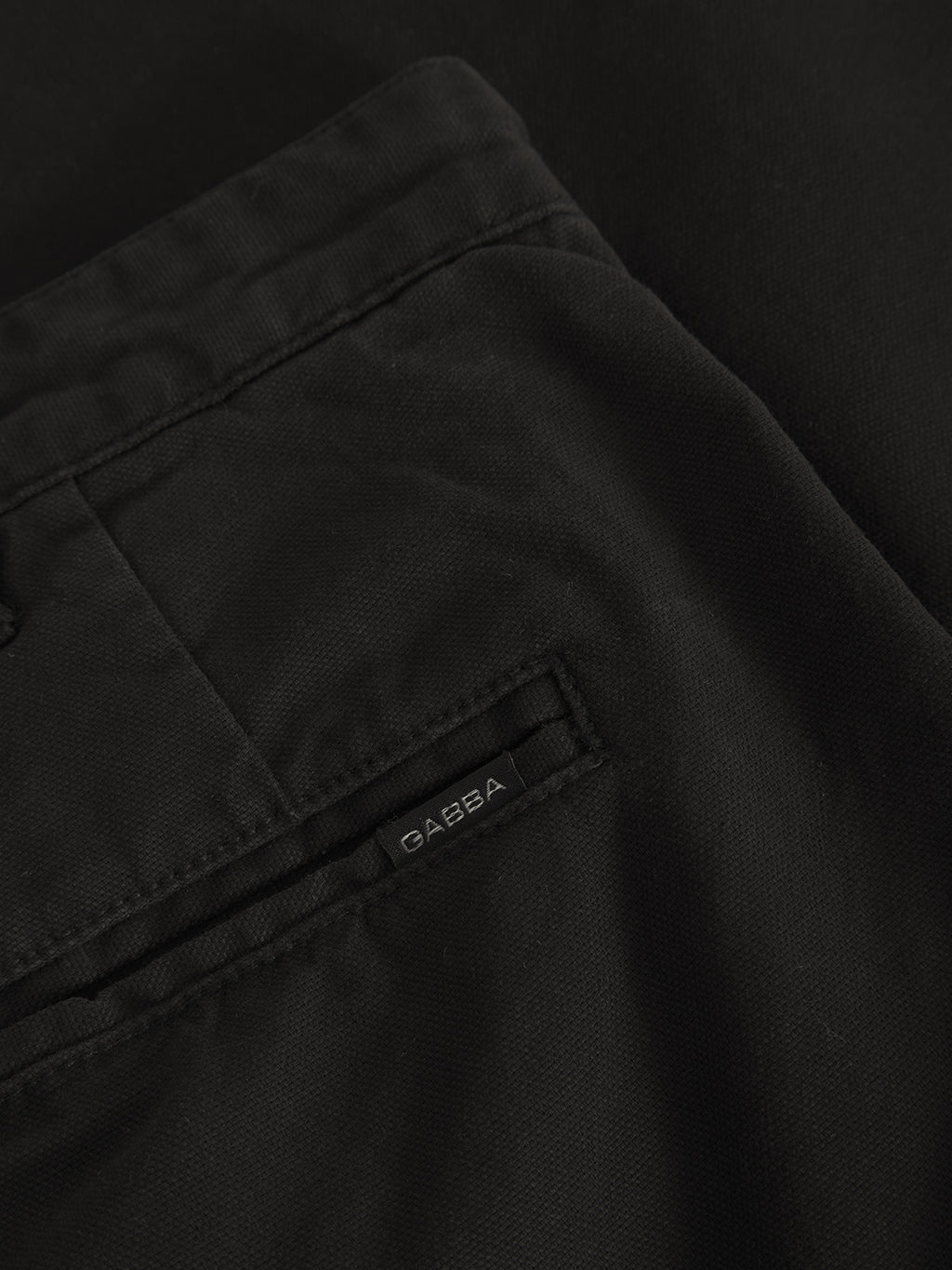 Close-up of Verona Ent - Meteorite fabric, featuring a pocket and a small Gabba label. The durable black material offers a contemporary look, likely part of loose straight fit pants or a jacket.