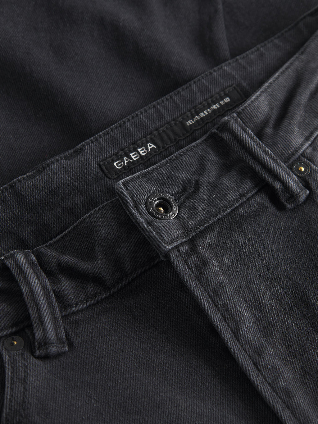 Close-up of grey denim jeans with belt loops, button, and visible stitching. The label reads Gabba with additional small text. The fabric has a textured appearance and faded effect typical of worn denim, from the Carl K4430 Limited line.